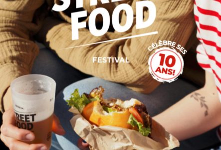 DR l'affiche du Geneva Street Food Festival 2025. Deux personnes sont assises côte à côte. L'une porte un pull marron clair, l'autre un t-shirt rayé rouge et blanc. Elles tiennent de la nourriture : un sandwich bien garni enveloppé dans du papier kraft et un verre de boisson portant l’inscription « Street Food Geneva ». Le tout est pris en photo en plein jour, dans une ambiance détendue et conviviale.
