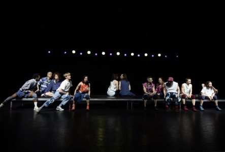 Sur cette image, il y a douze comédiens et comédiennes assis et séparés en trois groupes, il y sur les extrémités 2 groupes de 5 comédiens et un groupe de deux comédiens au centre de l'image. Chacun des comédiens à une expression de visage différente.