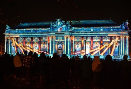 Public devant la façade illuminée du musée