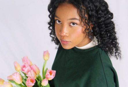 une image de l'artiste qui tient un bouquet de fleur