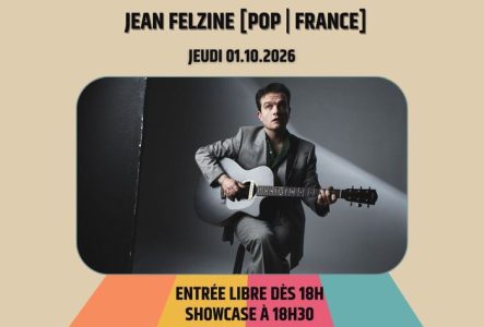 L'artiste sur un fond gris en studio avec une guitare à la main.