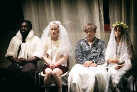 Quatre personnes en habits de mariage, assistantes ou ayant assisté à une cérémonie, sont assises sur des chaises, leurs visages exprimant une austérité profonde.