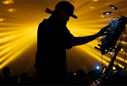 Un homme DJ en ombre sur un fond de lumière led jaune.