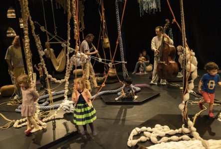 Des enfants et des artistes sur la scène parmi des cordes avec des noeuds qui pendent