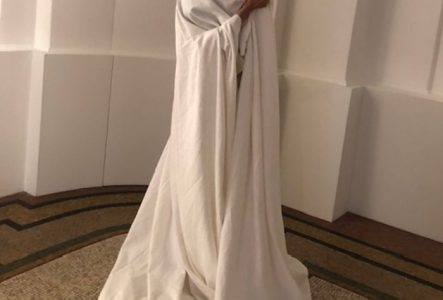 Femme recouverte d'un tissu blanc dansant dans une salle beaux-arts