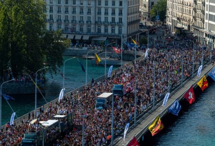 Sur cette image on peut voir une foule de personnes allant sur le pont du mont blanc à Genève. Au milieu de la foule on remarque des bus qui diffuse de la musique.