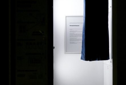 C'est l'image d'un photomaton dans le noir. Il y a de la lumière dans la cabine on aperçoit un petit rideau et un petit tabouret.