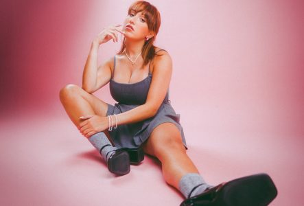 Lisa Pariente, assise au sol, sur un fond rosé.