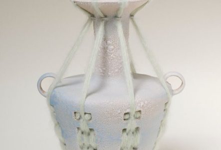 Photo d'un vase avec des perforations qui font support à un tissage en laine