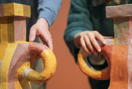 Deux personnes touchent la surface d’œuvres en céramique dans l'exposition "Marie Ducaté. Simultanés"