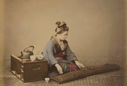 Deux personnes vêtues de blanc se tenant l’une contre l’autre, échangeant un baiser séparé par un voile blanc transparent.