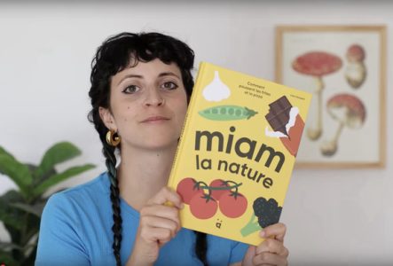Une photo en couleur qui représente Lisa Voisard qui tient son livre "Miam la nature" entre ses mains.