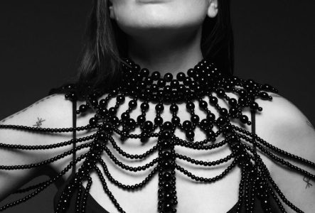Portrait en noir et blanc de Natalia Doco regardant en l’air. Elle porte un gros bijou en perles.