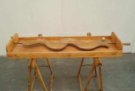 Jeu en bois avec un planche en bois et une poignée qui permet de guider une bille en bois sur un parcours sinueux.
