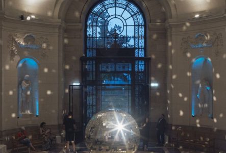 Public dans le hall du musée autour d'une boule à facettes