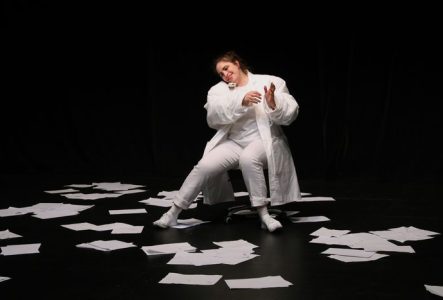 la comédienne en blanc au milieu de papiers qui virevoltent