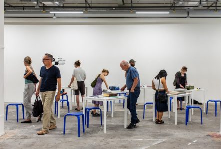 Huit personnes regardent des livres présentés durant l'édition 2024 du festival