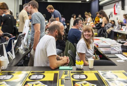 Aline Bovard Rudaz Photographie de la foire du livre photographique où les livres sont présentés sur des tables, entourés des éditeurs et des visiteurs qui les regardent et les feuillettent.