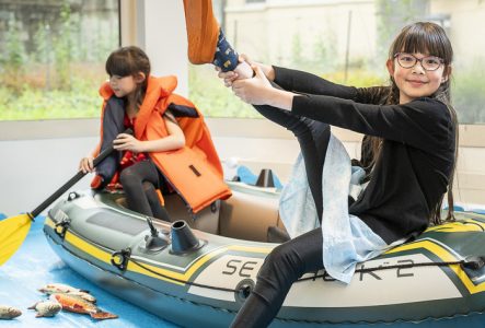 Greg Clément petite fille dans un bateau en plastique enfilant des palmes pour se déguiser en plongeur