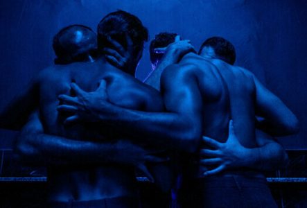 Quatre hommes s'enlacent de manière sensuelle