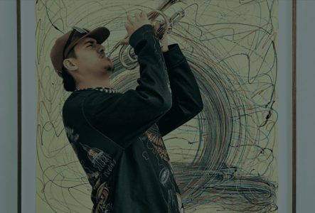 Un musicien jouant de la trompette devant une peinture.