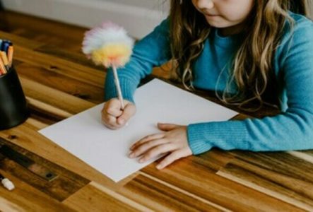 fillette écrivant avec un stylo pompom