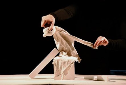 Une marionnette en chiffon blanc est assise sur des formes géométriques