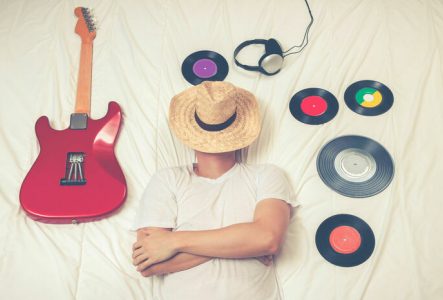 DR Une personne dort entouré de vinyles et d'une guitare électrique