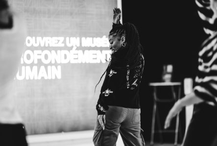 DR Photo d'un cours de danse au MEG. La professeurs et de côté et les participant-e-s de dos. Il y a des enfants et des adultes qui participent.