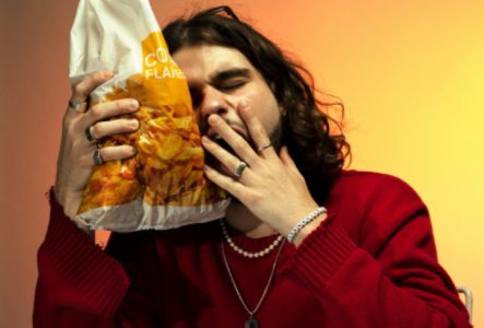 une image de l'artiste qui bâille avec un paquet de corn flakes dans la main.