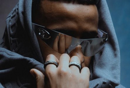 Photo centrée sur Stormy, portant des lunettes et un hoodie. Son regard, à la fois mystérieux et perçant, domine l’image.
