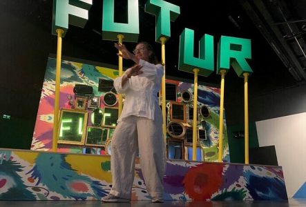 La  photo est prise dans l'exposition temporaire "Le futur, c'est quoi?". Une femme en position de Taiji effectue des mouvement devant le décor.