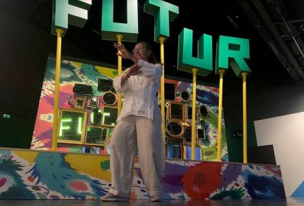 La  photo est prise dans l'exposition temporaire "Le futur, c'est quoi?". Une femme en position de Taiji effectue des mouvement devant le décor.