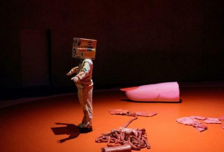 © Philip Frowein un interprète debout un carton en guise de masque. Des éléments de décors au sol: un doigt coupé, des viscères