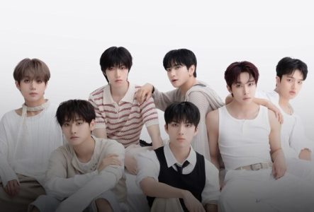 Photo des 7 membres du groupe assis parterre avec un fond blanc en arrière plan