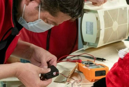 Un homme répare un ventilateur sur un établi.