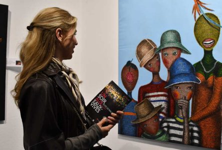 Une femme qui admire une peinture munie d'un flyer un soir aux Eaux-Vives