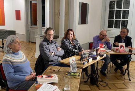 Des femmes et hommes assis à des tables présentant leurs livres