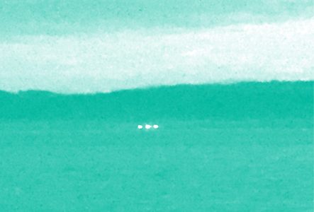 Trois point lumineux à l'horizon. la photo a un filtre de couleur.