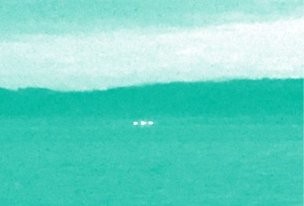 Trois point lumineux à l'horizon. la photo a un filtre de couleur.