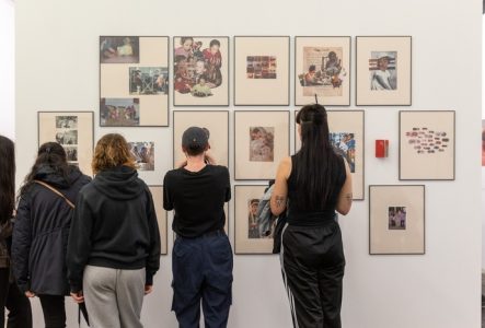 Photo représentant quatre femmes de dos, regardant une série de collages encadrés et accrochés en groupe au mur.