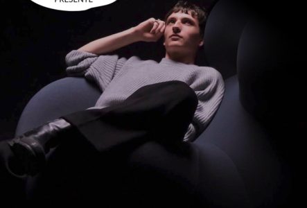 Inouie Affiche du concert de Victorien. On voit un jeune homme assis dans un fauteuil bleu sombre, portant un pull gris et un pantalon noir, éclairé sur fond noir. En haut à gauche, logo « Inouïe présente ». En bas à droite, texte « Victorien – 03.12.2025 – Le Groove, Genève ».